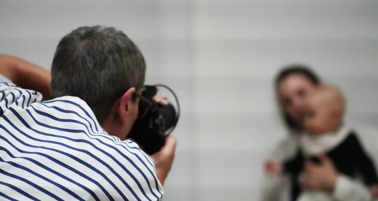 Blick über die Schulter des Fotografen, der im Studio ein Kind vor hellem Hintergrund aufnimmt